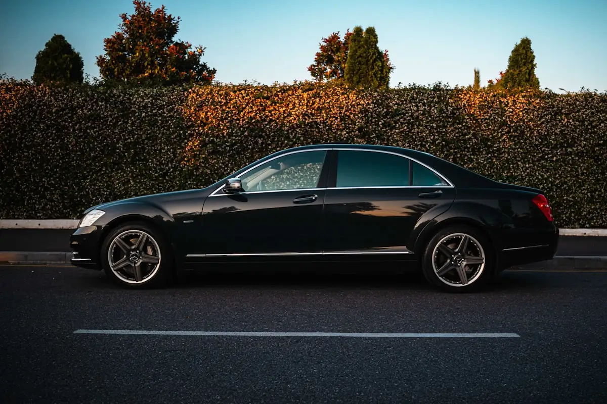 A private car waiting on a quiet street, driver discreetly out of frame