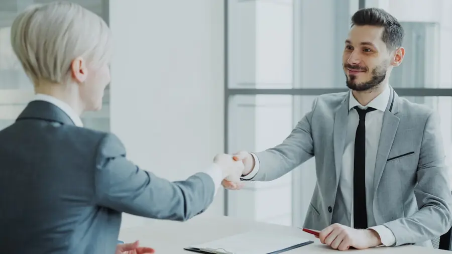 Two people shaking hands across a table